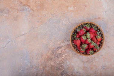 Mermerin üzerindeki ahşap bardakta kırmızı çilekler. Yüksek kalite fotoğraf