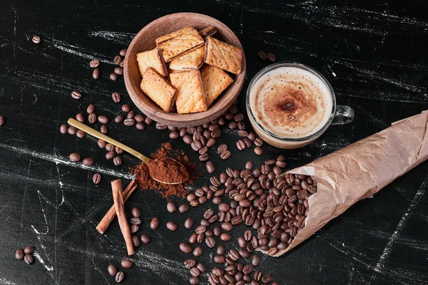 Coffee beans on black background with drink and crackers. High quality photo