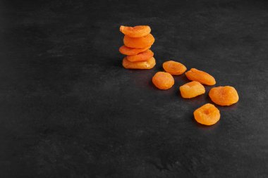 Yığının içinde kurumuş kayısılar ve siyah arkaplana yayılmış. Yüksek kalite fotoğraf