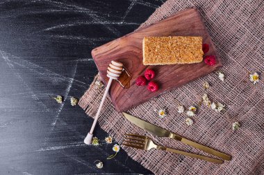 Kurumuş papatyalarla süslenmiş ballı pasta ve koyu mermer masada böğürtlenler. Yüksek kalite fotoğraf