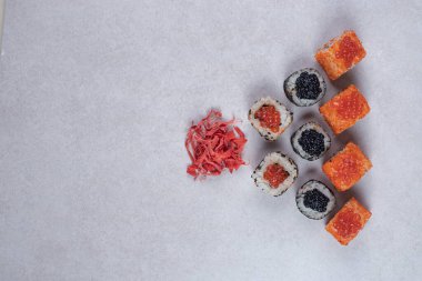 Maki ve California suşisi beyaz arka planda zencefil turşusuyla yuvarlanıyor. Yüksek kalite fotoğraf