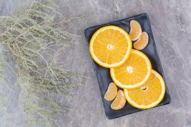 Siyah tabakta portakal ve mandalina dilimleri. Yüksek kalite fotoğraf