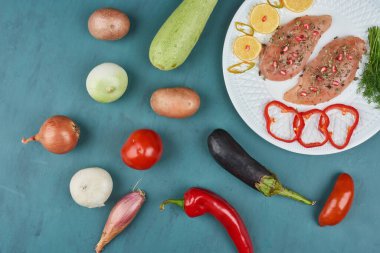 Çiğ tavuk filetosu, sebze ve otlarla dolu beyaz bir tabakta. Yüksek kalite fotoğraf