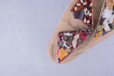 Üçgen şeklinde çikolatalı pasta dilimleri, fındıklı ve ahşap tabakta meyveler. Yüksek kalite fotoğraf