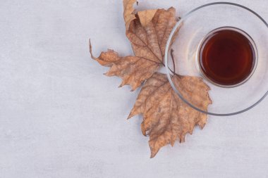 Beyaz yüzeyinde kurumuş yapraklar olan bir bardak çay. Yüksek kalite fotoğraf