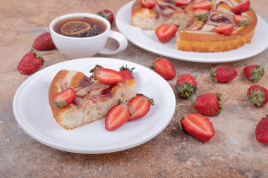 Kırmızı şuruplu çilekli turta, meyve ve bir fincan çay. Yüksek kalite fotoğraf