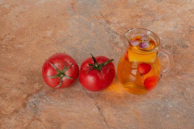 Mermer zemin üzerinde bir kavanoz meyve suyu ve taze domates. Yüksek kalite fotoğraf