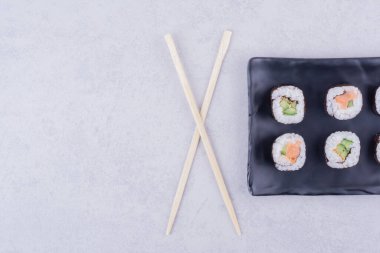 Sake maki somon ve avokado ile siyah seramik tabakta yuvarlanır. Yüksek kalite fotoğraf