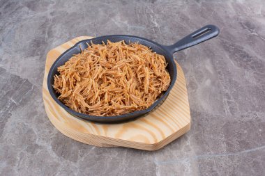 Mermer arka planda siyah bir tavada pişirilmiş makarna. Yüksek kalite fotoğraf