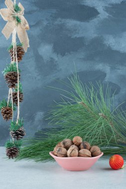 Ceviz dolu pembe bir tabak ve mermer arka planda kırmızı bir Noel topu. Yüksek kalite fotoğraf