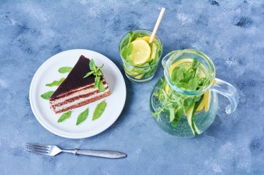 Beyaz tabakta bir dilim çikolatalı kek ve mojito kokteyli. Yüksek kalite fotoğraf