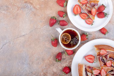 Kırmızı şuruplu çilekli turta, meyve ve bir fincan çay. Yüksek kalite fotoğraf