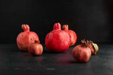 Siyah zemin üzerinde küçük ve büyük şekilli kırmızı narlar. Yüksek kalite fotoğraf