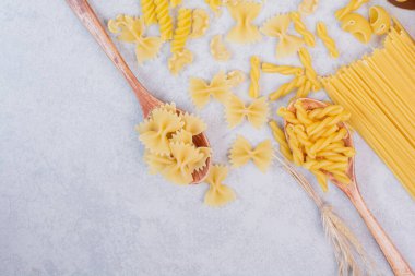  Beyaz arka planda çeşitli makarna şekilleri ve kaşıklar. Yüksek kalite fotoğraf