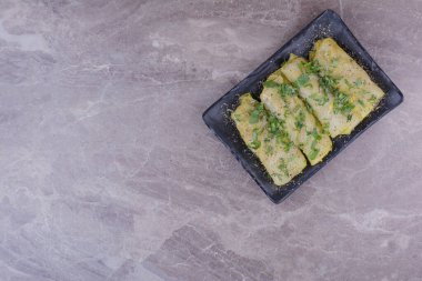 Siyah seramik tabakta doğranmış bitkilerle birlikte beyaz lahana ambalajları. Yüksek kalite fotoğraf