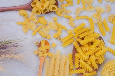 Beyaz arka planda buğday ve kaşıklarla pişmemiş taze makarna. Yüksek kalite fotoğraf