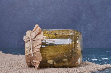 Mavi arka planda cam kavanozda yünlü masa örtüsü ile ev yapımı salatalık turşusu. Yüksek kalite fotoğraf