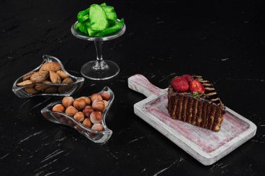 Tahtanın üzerinde fındık ve avokado dilimleri olan bir dilim çikolatalı pasta. Yüksek kalite fotoğraf