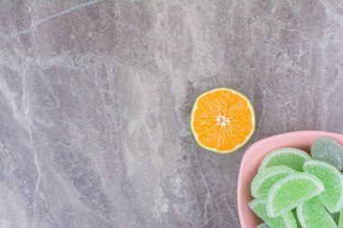 Pembe bir tabak marmelat ve mermer arka planda bir dilim portakal. Yüksek kalite fotoğraf