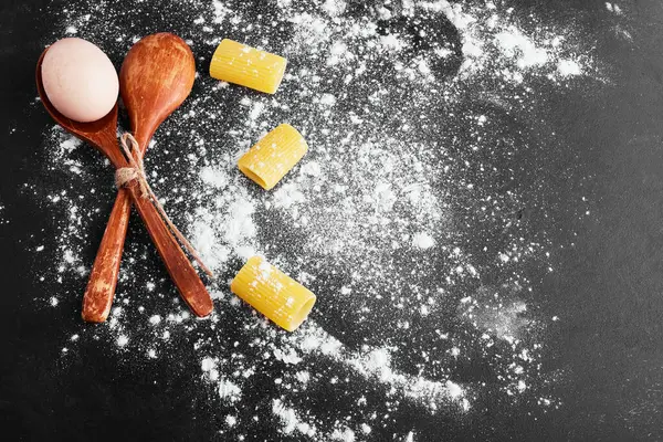 Makarna siyah arka planda izole edilmiş. Un ile kaplanmış. Yanında da yumurta var. Yüksek kalite fotoğraf