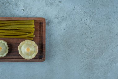 Lezzetli mini kabak turşusu ve mermer arka planda bir tahtaya yapışan sopalar. Yüksek kalite fotoğraf