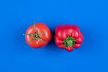 Taze domates ve kırmızı dolma biber mavi arka planda izole edilmiş. Yüksek kalite fotoğraf
