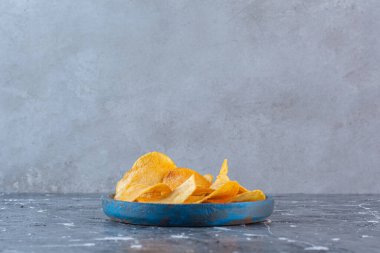 Tahta tabakta, mermer zeminde gevrek, baharatlı patates cipsi. Yüksek kalite fotoğraf
