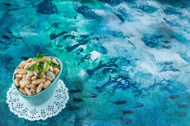 Mavi arka planda maydanozlu bir kase beyaz fasulye. Yüksek kalite fotoğraf