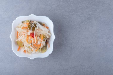 Mermer arka planda, kâsede lezzetli sebze turşusu. Yüksek kalite fotoğraf