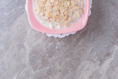 Sağlıklı gevreklerle dolu pembe bir tabak ve gri arka planda süt. Yüksek kalite fotoğraf