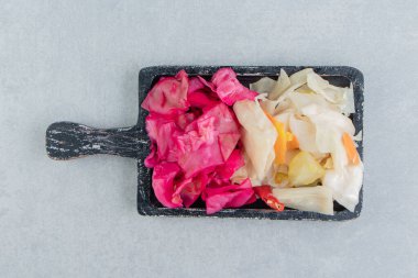 Mermer zemin üzerinde lezzetli kırmızı ve yeşil turşulu lahana turşusu. Yüksek kalite fotoğraf