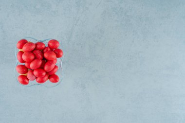 Beyaz arka planda tatlı kırmızı şekerlerle dolu cam bir tabak. Yüksek kalite fotoğraf