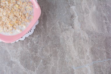 Sağlıklı gevreklerle dolu pembe bir tabak ve gri arka planda süt. Yüksek kalite fotoğraf