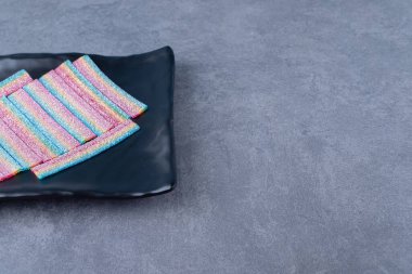 Ahşap tabakta, mermer zeminde çok renkli jöle şekerler. Yüksek kalite fotoğraf