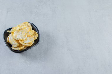 Taş zemin üzerinde siyah bir kase lezzetli pirinç cipsi. Yüksek kalite fotoğraf