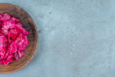 Mavi arka planda, ahşap bir tabakta kırmızı mayalanmış lahana turşusu. Yüksek kalite fotoğraf