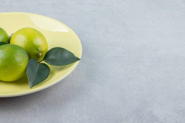 Sarı tabakta yaprakları olan lezzetli limon meyveleri. Yüksek kalite fotoğraf