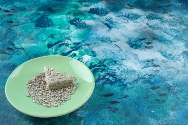 Dilimlenmiş, lezzetli ayçiçeği halkası, tabakta ve mavi arka planda tohumlar var. Yüksek kalite fotoğraf