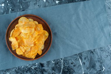 Mermer zeminde, kumaş parçalarının üzerinde patates cipsi var. Yüksek kalite fotoğraf