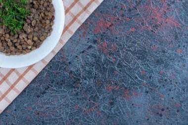 Masa örtüsünde fasulye ve otlarla dolu beyaz bir tabak. Yüksek kalite fotoğraf