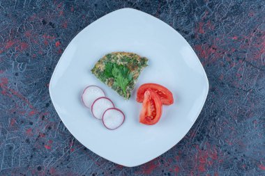 Mavi bir tabak omlet ve dilimlenmiş turpla dilimlenmiş domates. Yüksek kalite fotoğraf