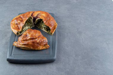 Siyah kesme tahtasına yeşillik doldurulmuş turta. Yüksek kalite fotoğraf