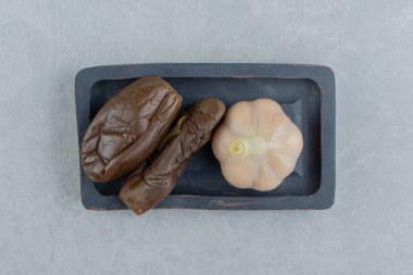 Sarımsak ve turşu, tahta tabakta, mermer arka planda. Yüksek kalite fotoğraf