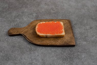  Tahta kesme tahtasının üzerinde kırmızı havyarlı bir dilim ekmek. Yüksek kalite fotoğraf