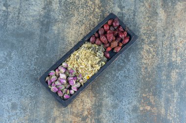 Siyah tabakta kurumuş güller, papatyalar ve gül kalçaları. Yüksek kalite fotoğraf