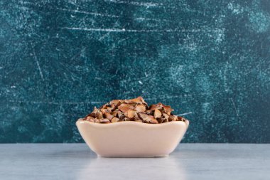 Taş zeminde bir sürü gevrek tohumu olan bej bir kase. Yüksek kalite fotoğraf