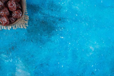 Mavi arka planda, bir kasede kurutulmuş erik. Yüksek kalite fotoğraf