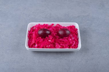 Mayalanmış kırmızı lahana, mermer arka planda, kasede erik ve yalan söyler. Yüksek kalite fotoğraf