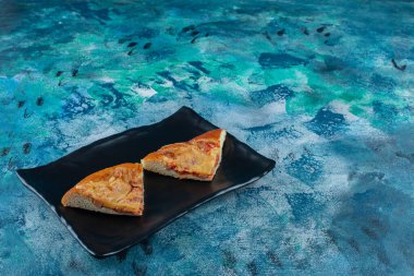 Siyah tabakta, mermer arka planda nefis bir mini pizza. Yüksek kalite fotoğraf