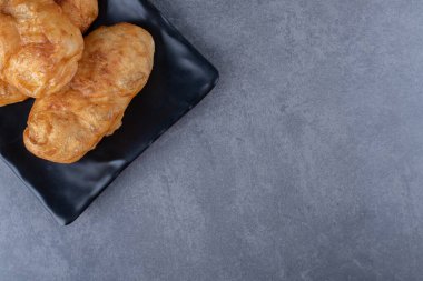 Taze pişmiş Rus hamur işi pirozhki ahşap tabakta, mermer zemin üzerinde. Yüksek kalite fotoğraf